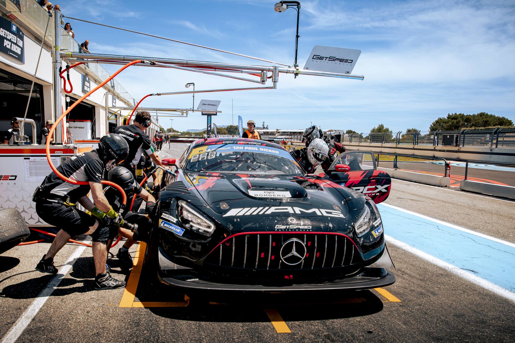 Mercedes-AMG GT3 noire à l'arrêt au stand, ravitaillement