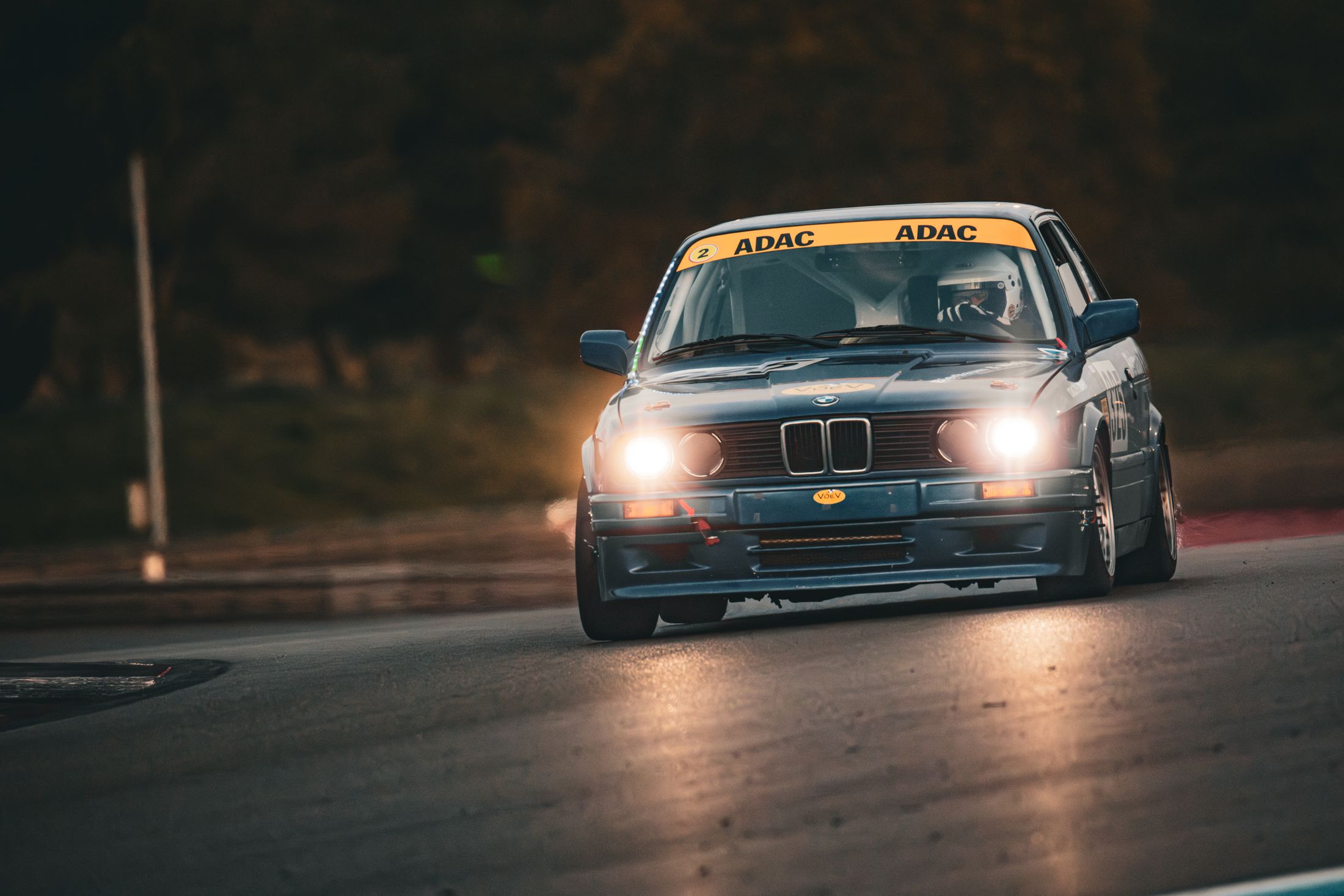 BMW E30 grise ADAC, phares allumés de nuit