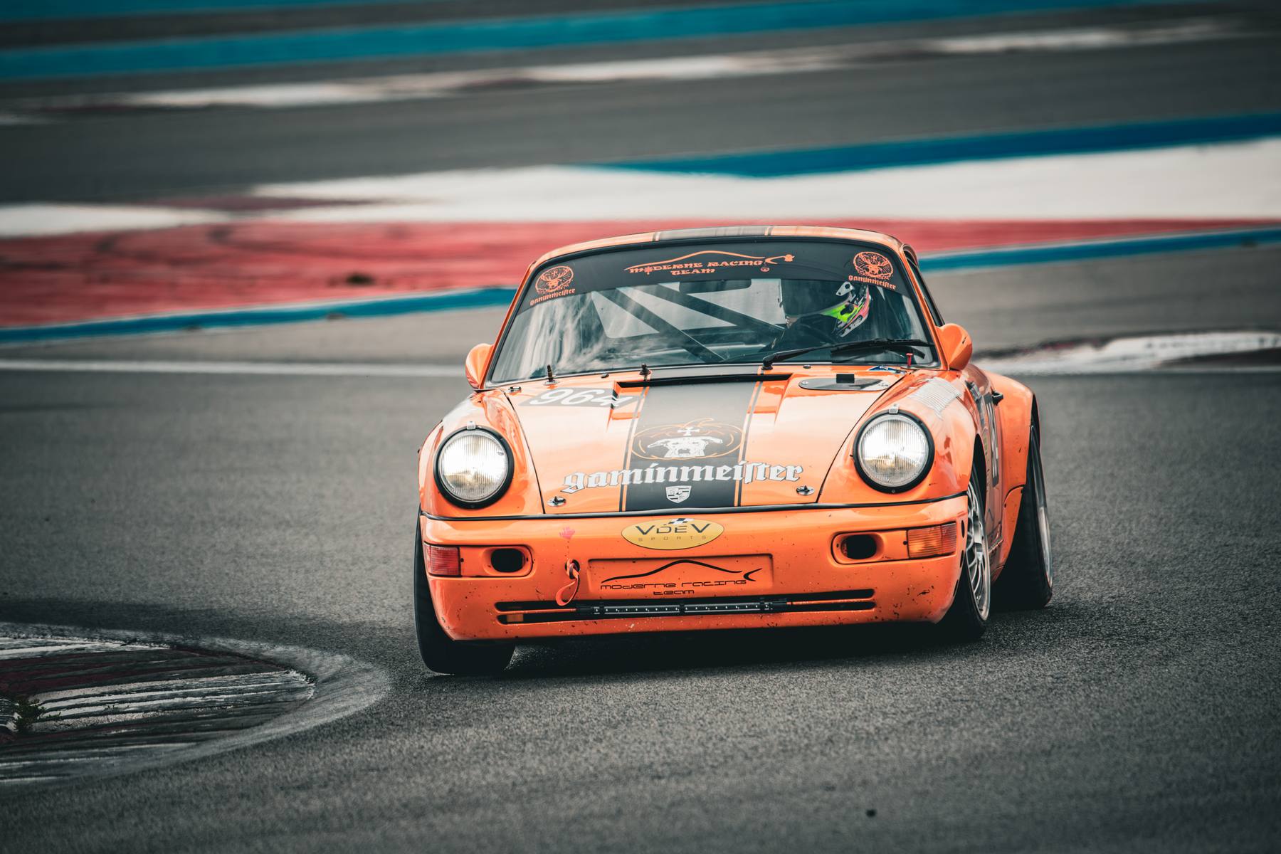 Porsche 911 orange, plan serré de face en virage