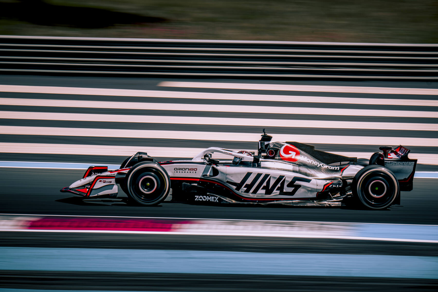 Haas VF-23 MoneyGram en panning vue de profil sur la grande ligne droite du Paul Ricard, barrières rayées en arrière plan, test TPC 30 mai 2025