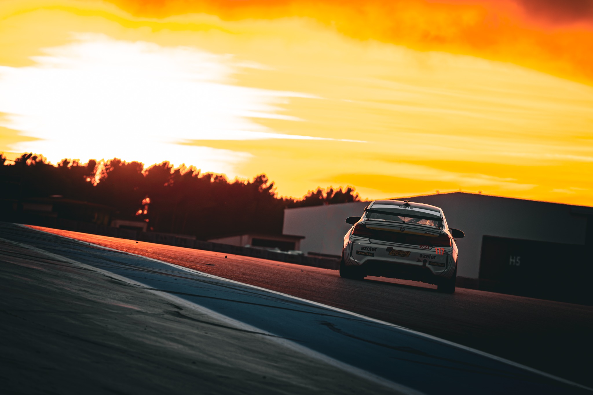 Voiture GT numéro 117 montant vers le coucher du soleil sur le circuit Paul Ricard