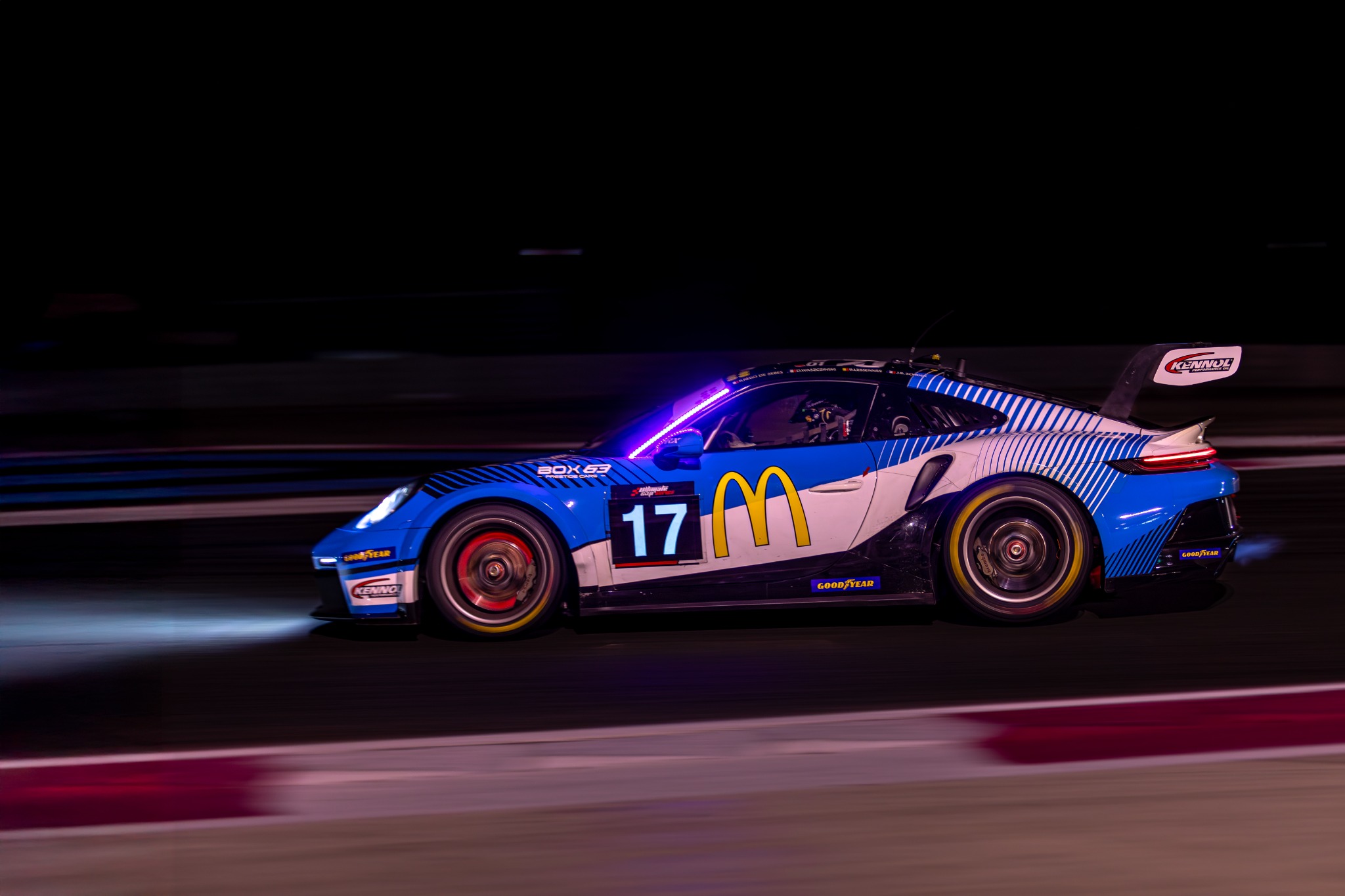 Porsche numéro 17 éclairée de bleu en pleine vitesse pendant une course nocturne