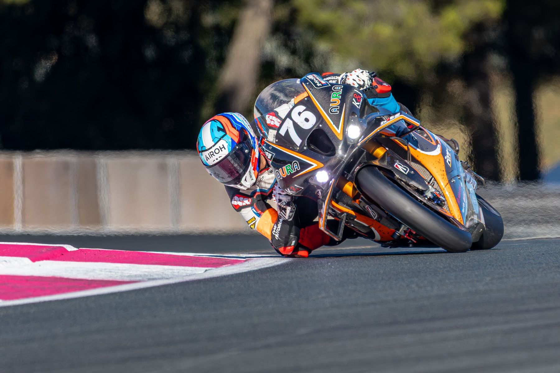 Moto noire et orange Aura n°76 en pleine inclinaison