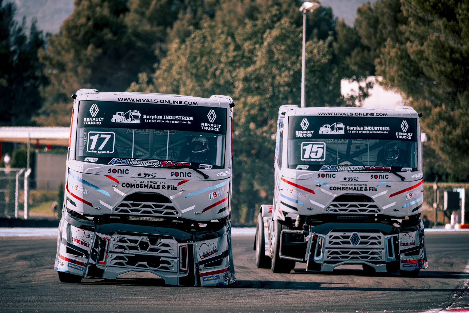 Deux camions de course n°17 et n°15 alignés au paddock