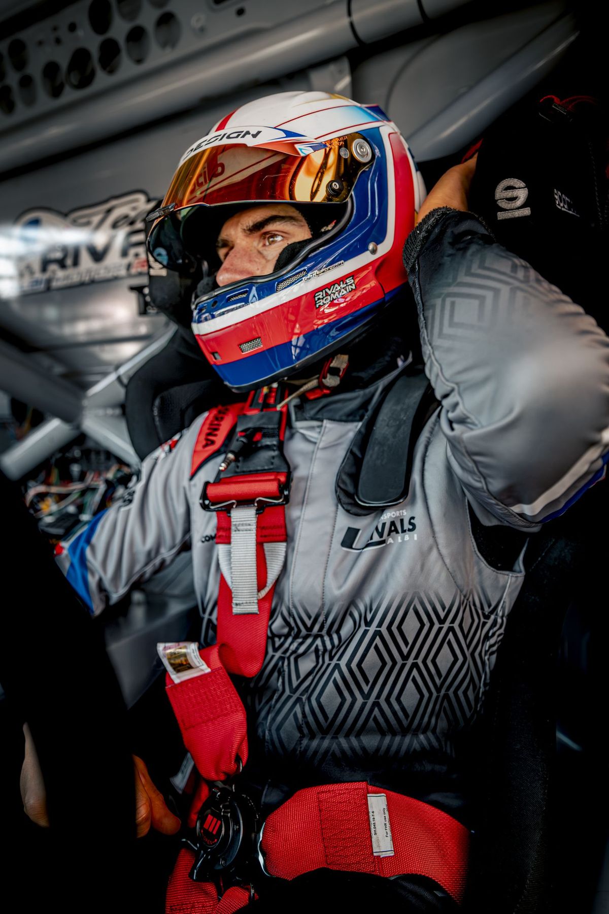 Portrait pilote ajustant son casque, combinaison bleue et rouge