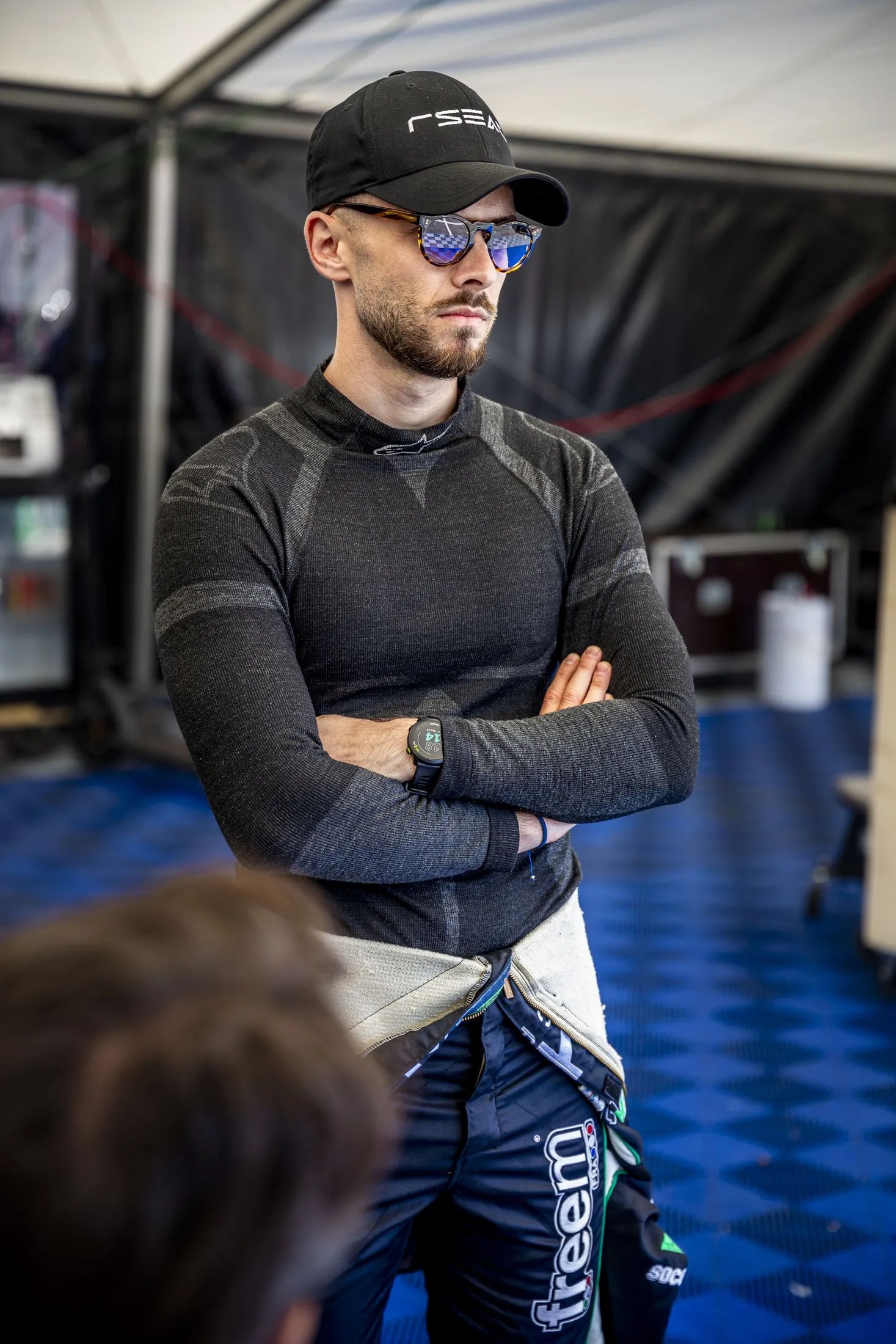 Pilote bras croisés dans le paddock