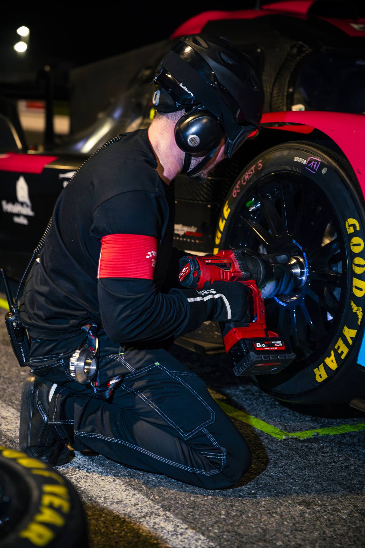 Mécanicien accroupi au changement de roue, gants rouges