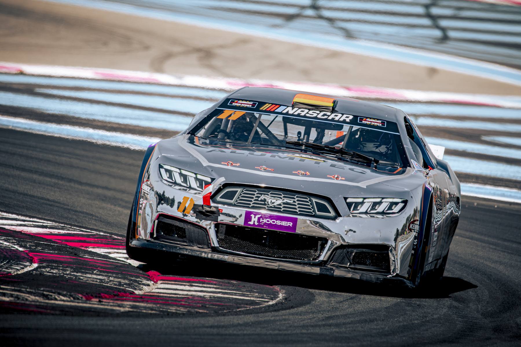 Stock-car blanc et argent, plan serré de face en virage