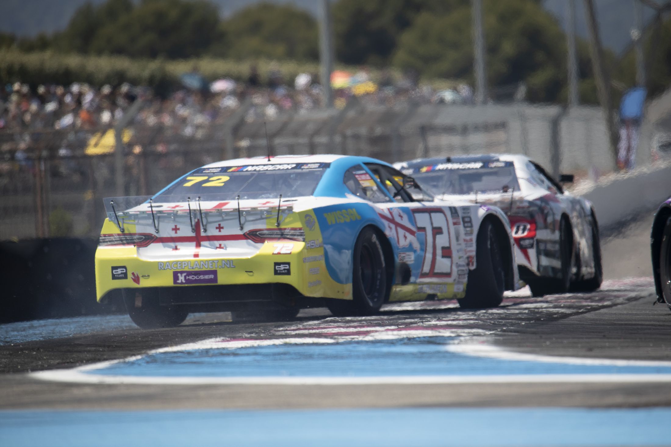 Stock-car jaune et noir, plan arrière en sortie de virage