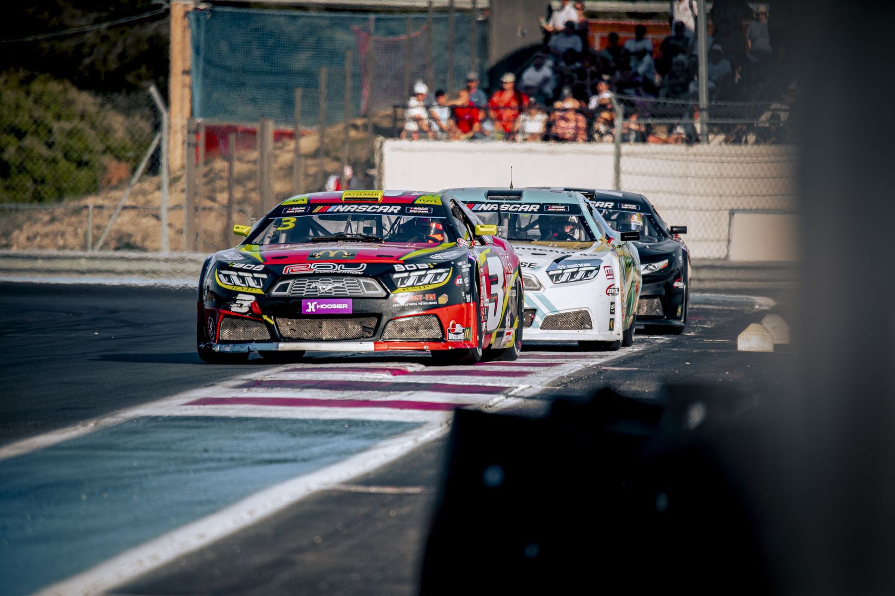 Peloton de stock-cars en virage serré