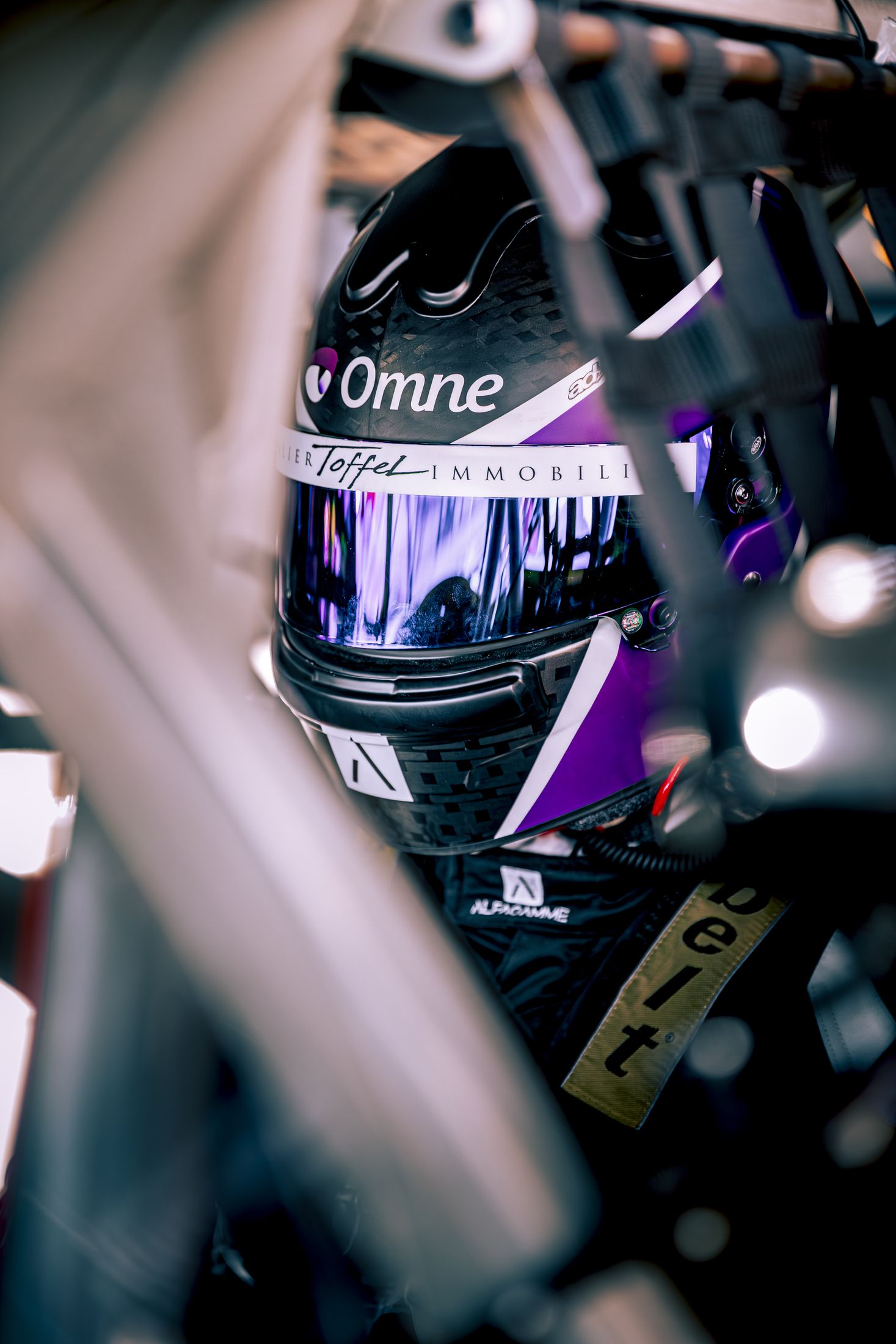 Portrait pilote, casque violet et noir, main sur l'arceau