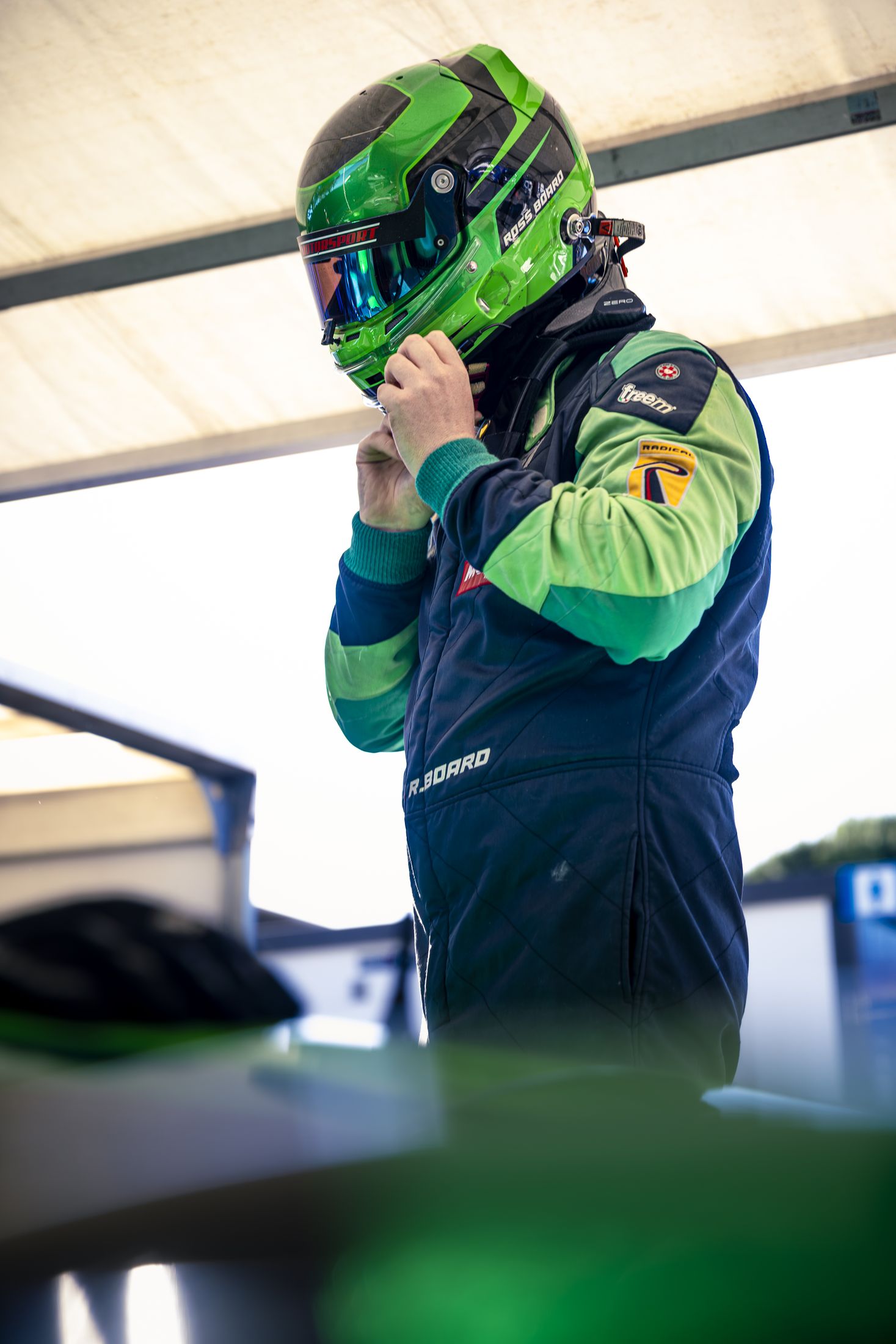 Portrait pilote debout, combinaison verte, ajustant son casque