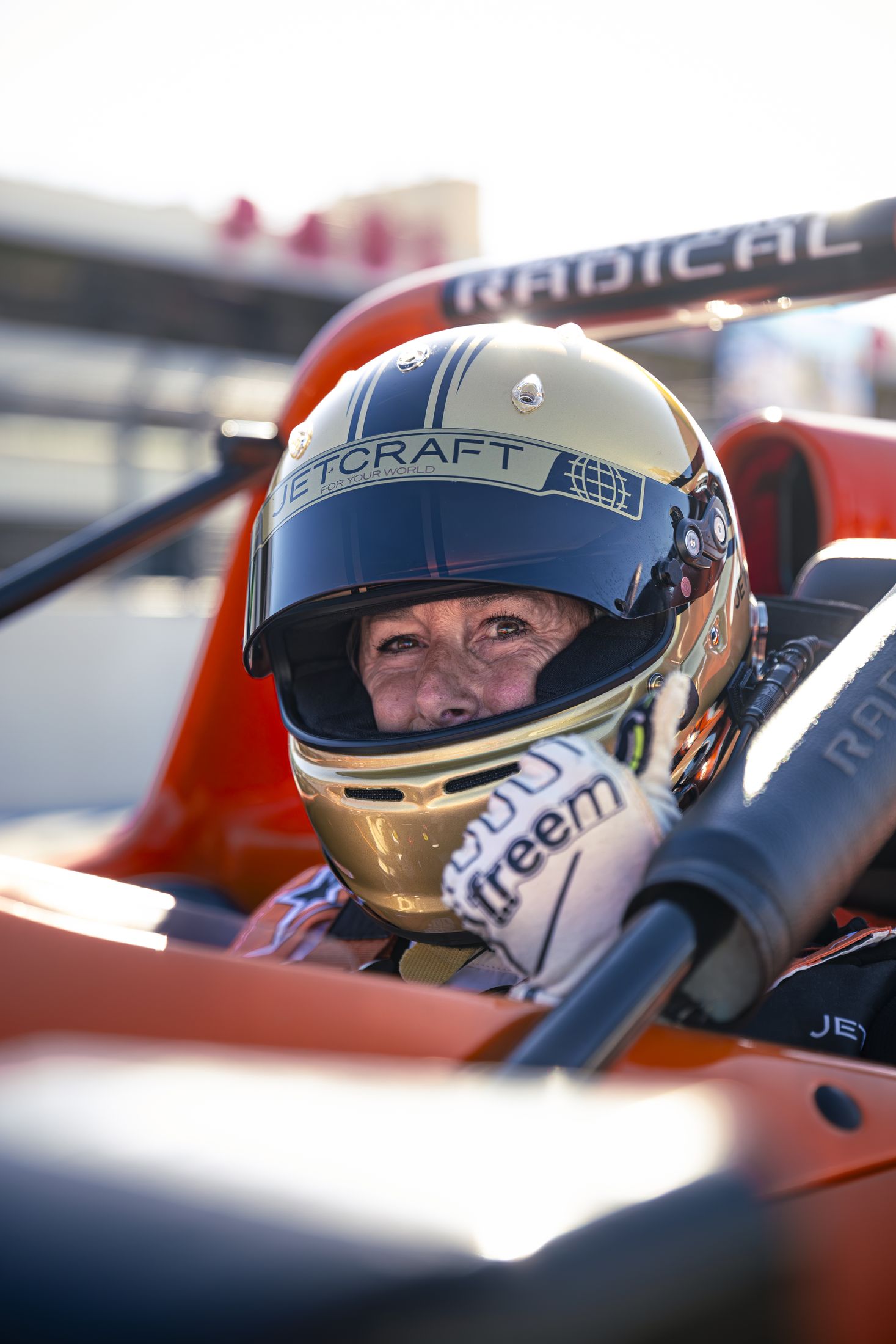 Portrait pilote souriant, casque doré et blanc Radical