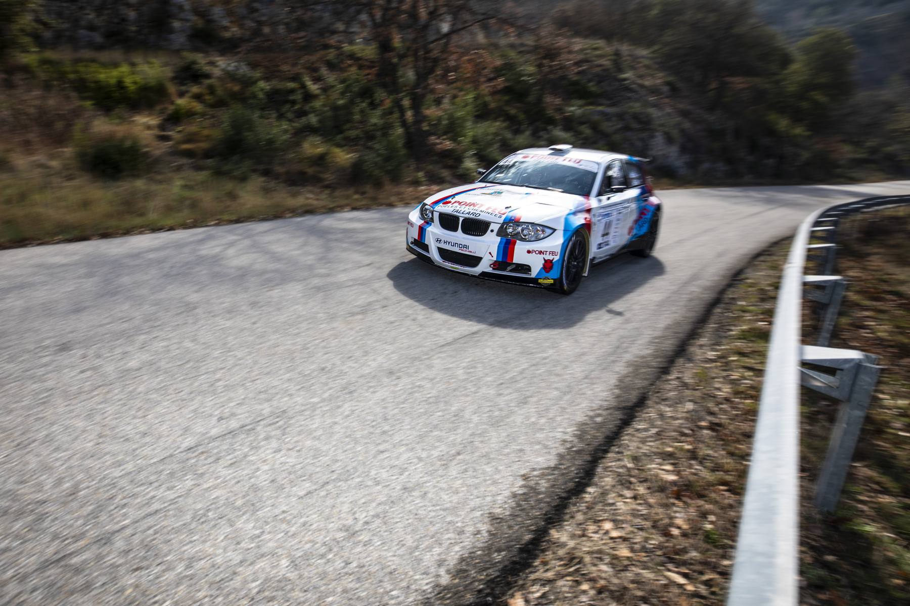 BMW de rallye en virage le long des glissières de sécurité
