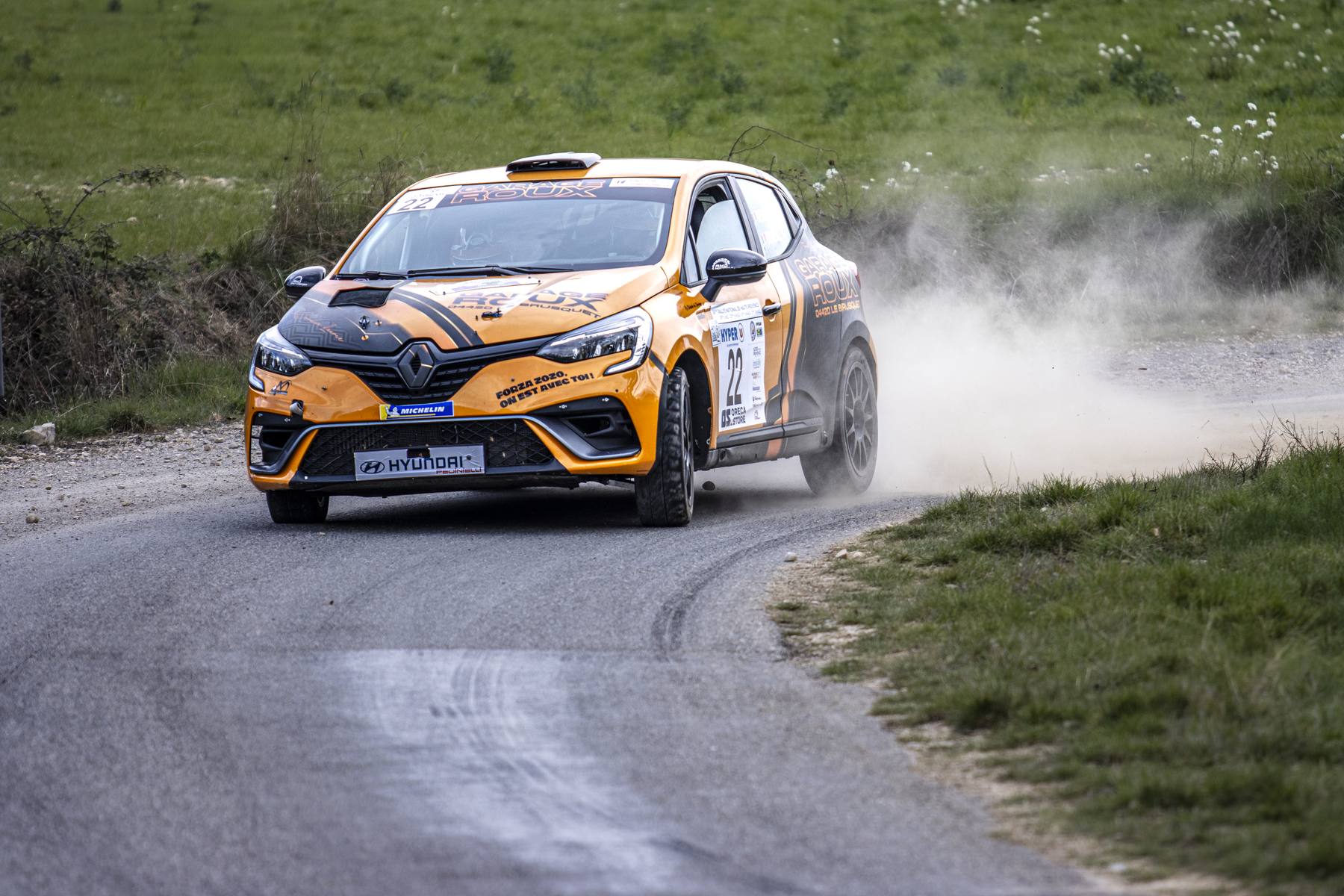 Renault Clio orange en glisse, nuage de poussière
