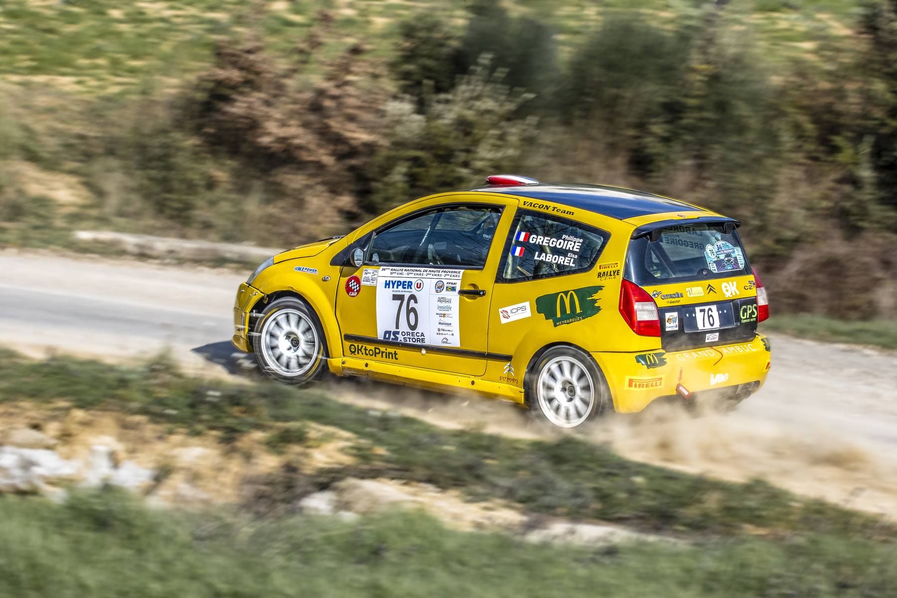 Voiture de rallye jaune n°76 en pleine attaque, poussière